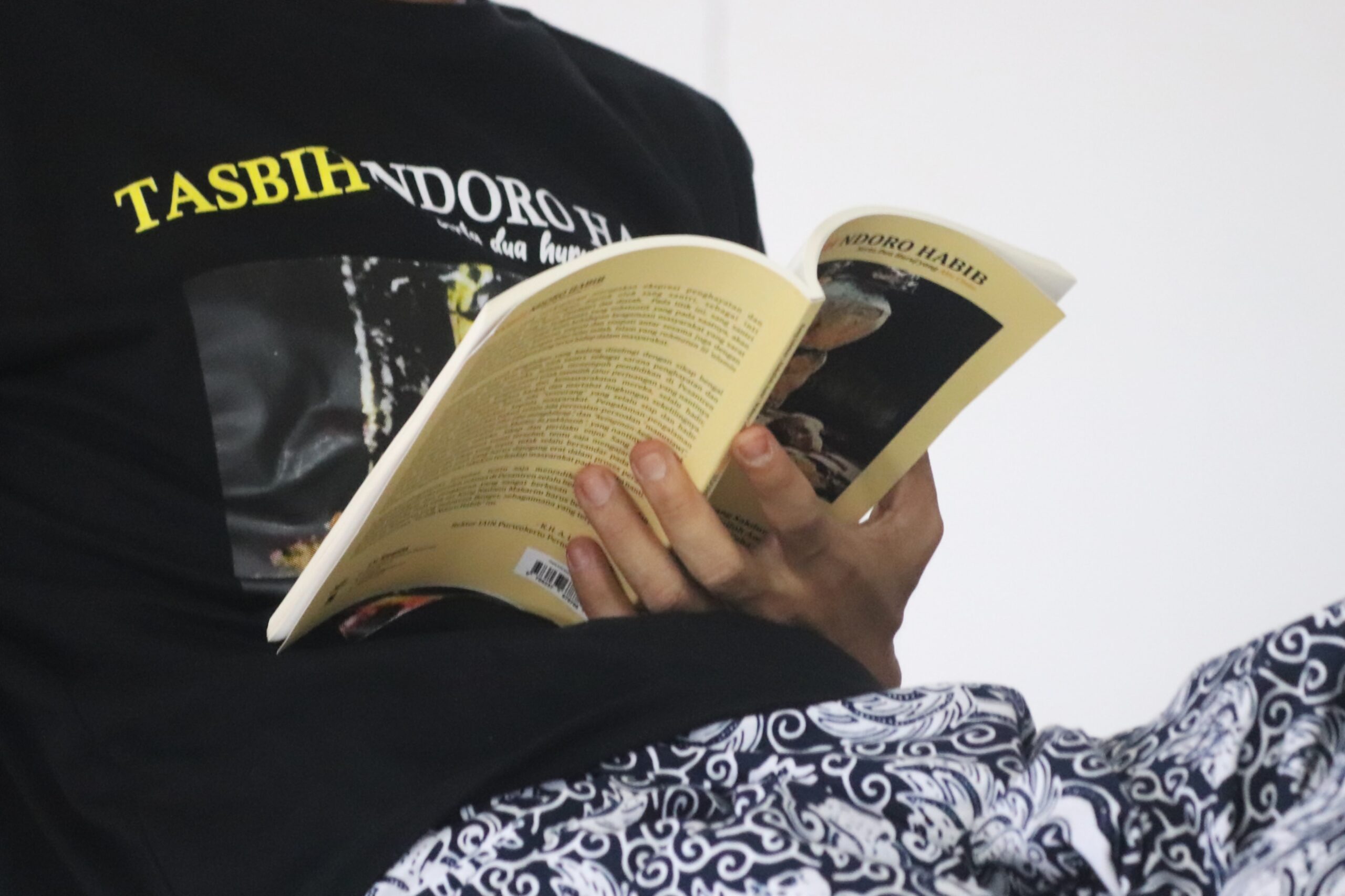 person reading book on black and white textile